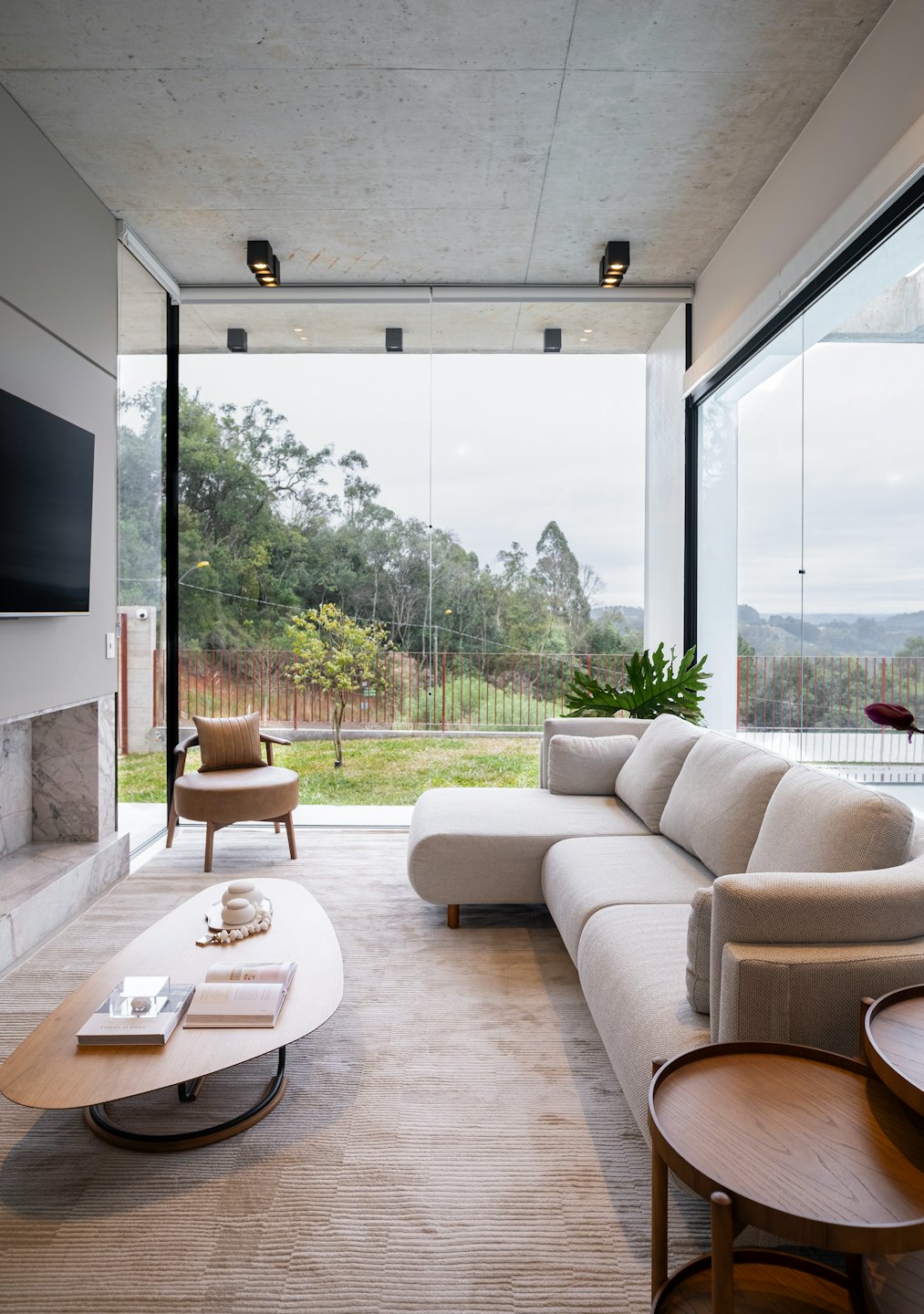 Modern living room with grey sofa and armchair by large windows.