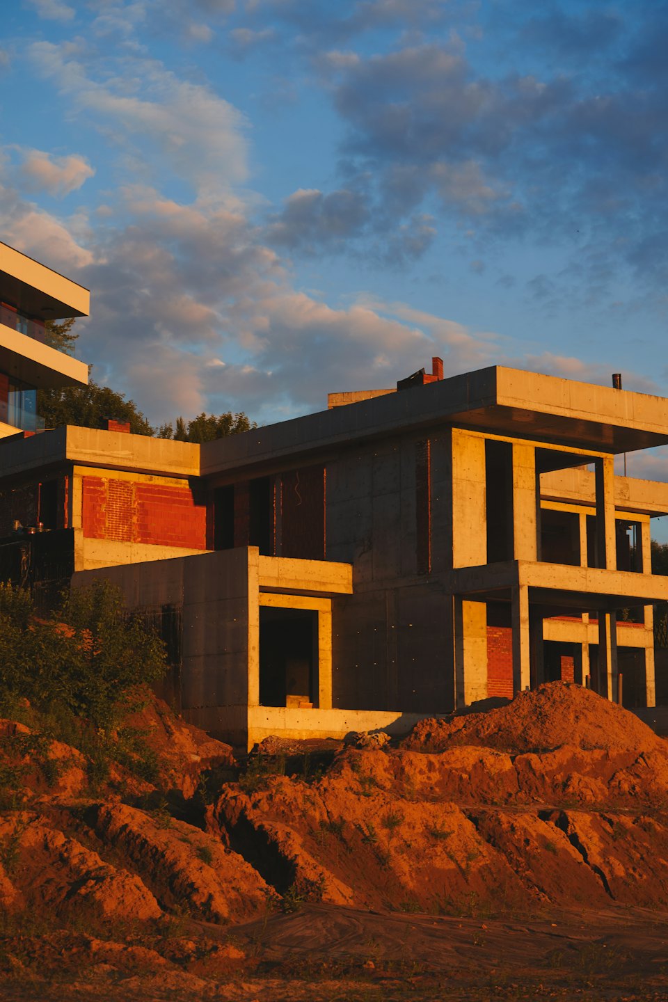Modern house under construction with concrete and brick walls at sunset.