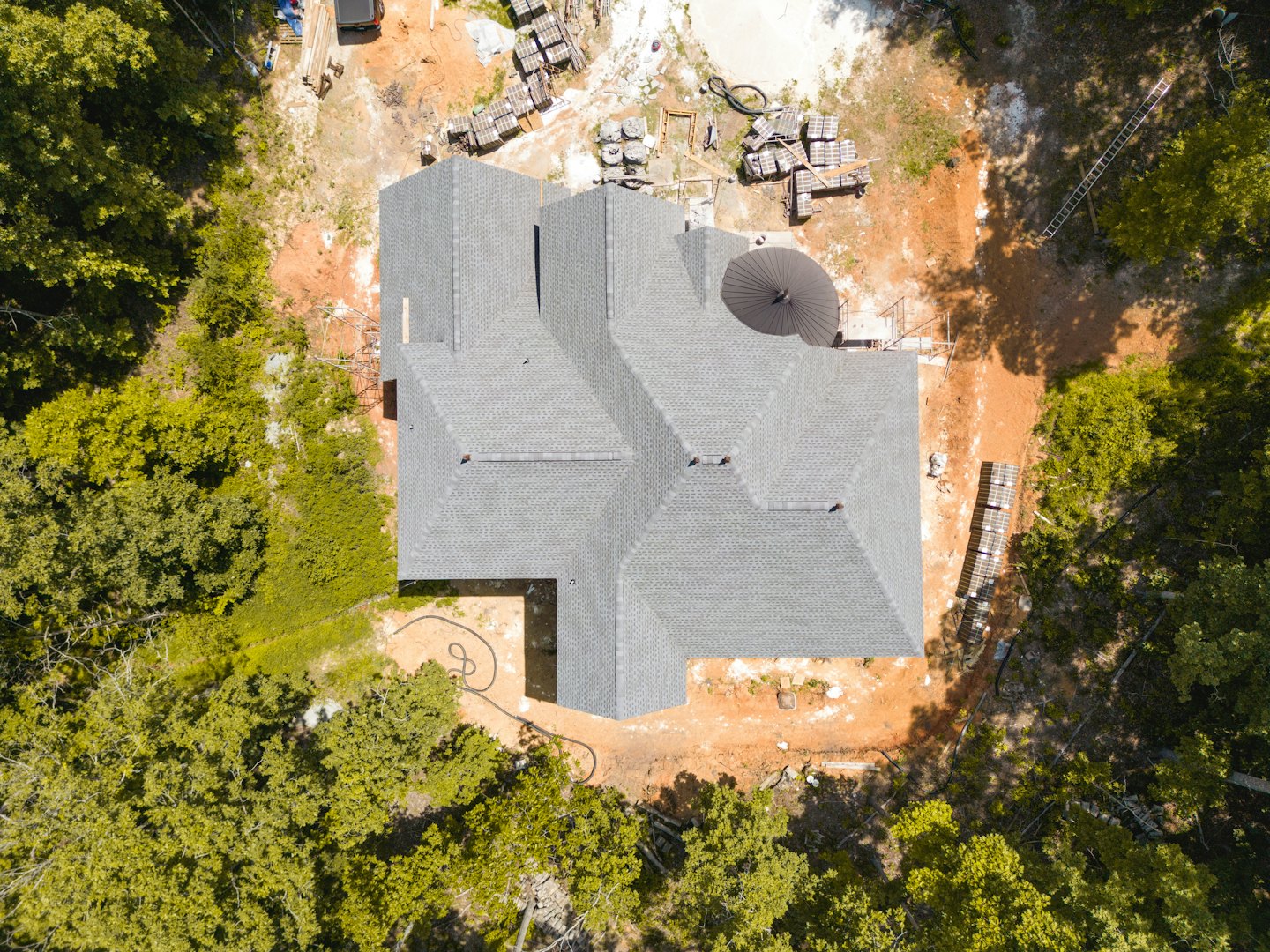 Newly built house with grey roof surrounded by trees.