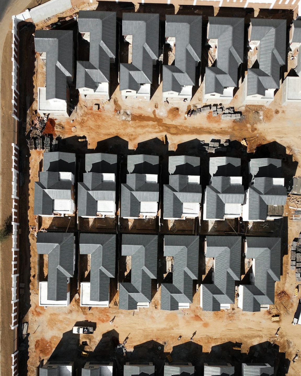 Aerial view of new houses under construction with workers on site.